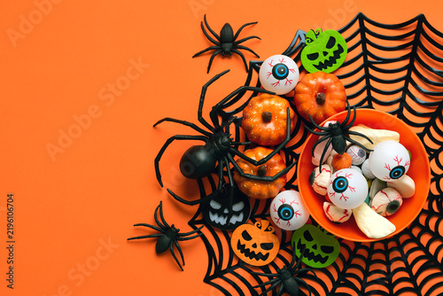 Top view of plate with Halloween candy,spiders,Halloween pumpkins and spider web with copy space for text. Halloween concept background