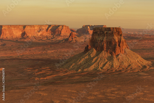 Aerial view of Lake Powell landscape featuring dramatic red rock mesas, rugged desert terrain, and golden hour light in Page, Arizona, United States.