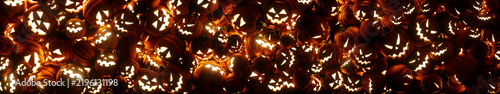 Glowing jack-o-lanterns Pumpkins with spooky faces fill the screen, ultra wide panoramic background for Halloween 