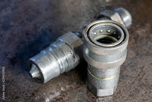 Foto Steel hydraulic quick disconnect couplers lie on dirty workshop metal workbench