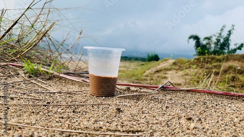 фотографія Discarded plastic cup with brown residue left on the ground in nature