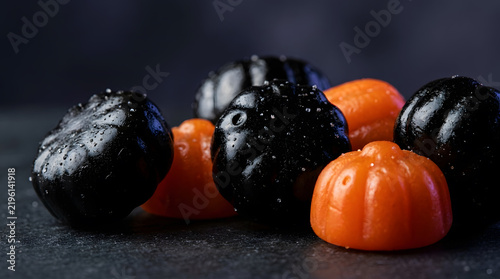 Close up of black and orange pumpkin shaped halloween candies on dark background