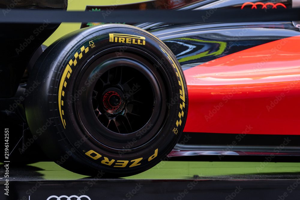 Obraz premium NEW YORK, USA – SEPTEMBER 16, 2026: a Formula 1 race car wheel with Pirelli tire and glossy red black bodywork in close-up.