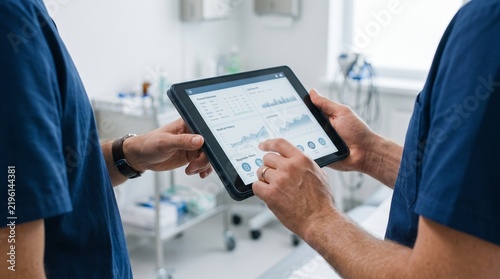Medical professionals reviewing patient health data on a digital tablet in a hospital setting.