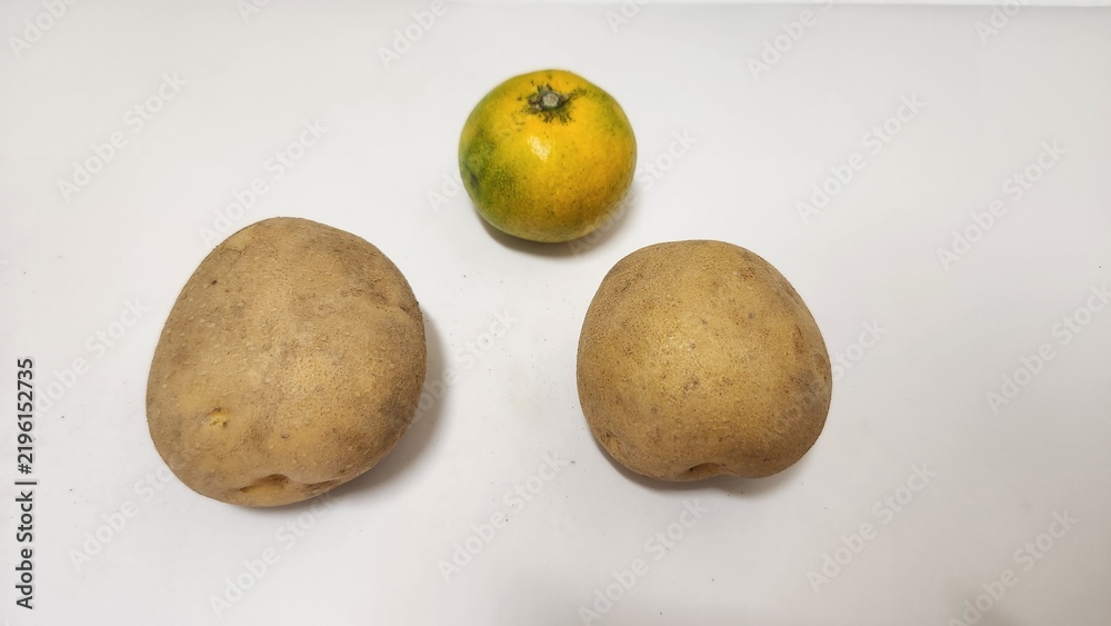 Fototapeta premium Potato, unripe tangerine, paper, white, background, staple crop, three potatoes, simple, simple background