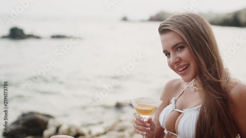 Woman enjoying a drink by the beach during sunset in summer