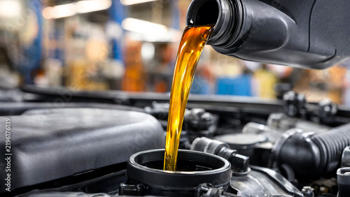 Fresh motor oil pouring into a car engine during a routine maintenance service