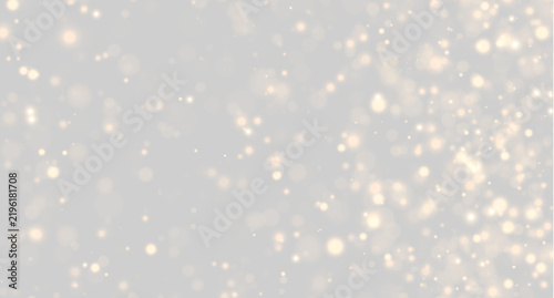 Golden bokeh particles scatter across a dark background. The lights show various sizes and soft round shapes with a warm glowing effect. This image suits festive, celebratory, or.