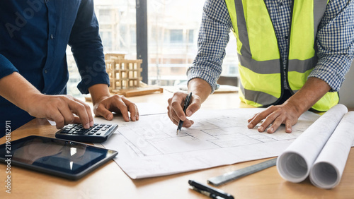 Engineers reviewing architectural blueprints at a desk with a model