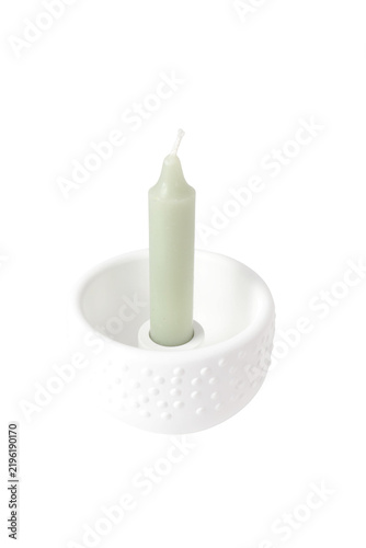 Fotografie light green taper candle standing in a modern round matte white plaster candle h