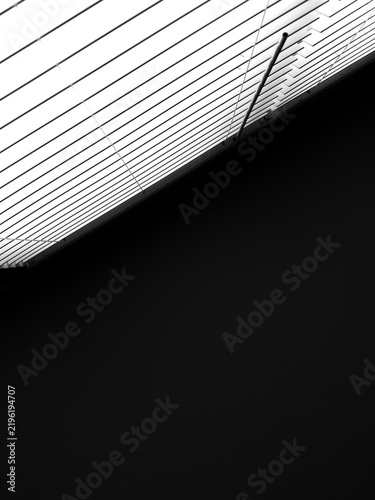 Canvastavla Upside-down view of horizontal window blinds and dark ceiling in a contemporary apartment on a sunny day, in black and white