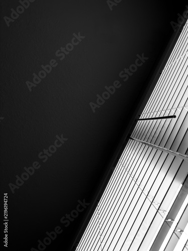 Konstfotografi Upside-down view of horizontal window blinds and dark ceiling in a contemporary apartment on a sunny day, in black and white