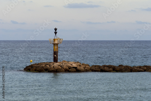 Coastal Lighthouse on Rocky Breakwater in the Mediterranean Sea
