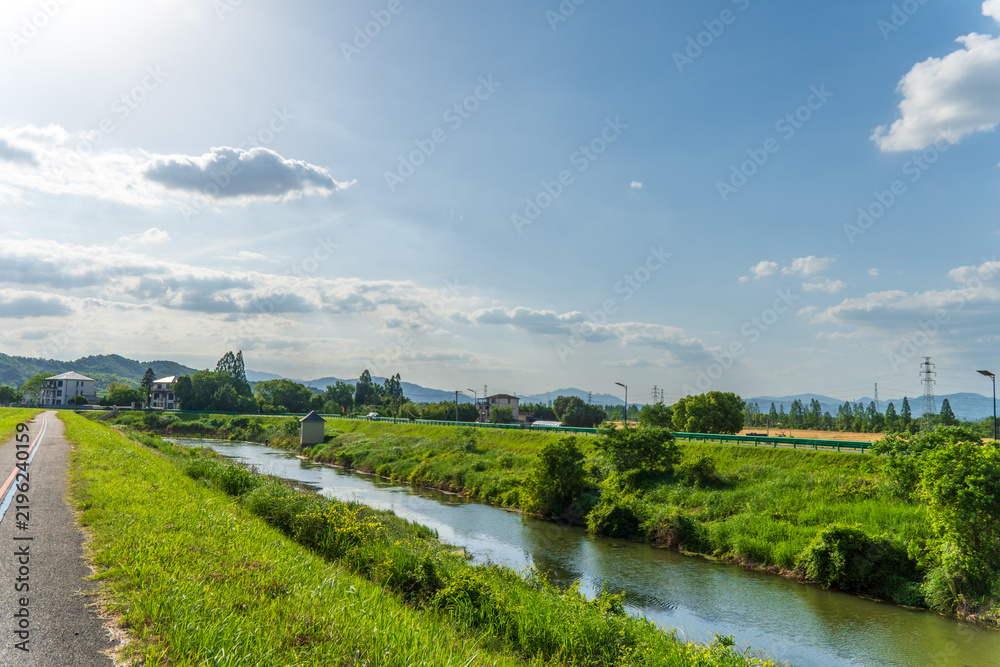 Obraz premium Rural River Landscape with Green Banks Under a Bright Blue Sky