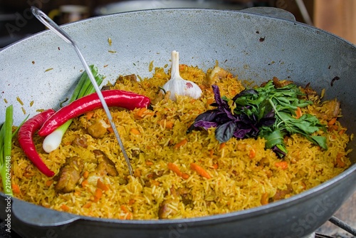 Fresh yellow rice cooks inside a heavy metal pot outdoors.