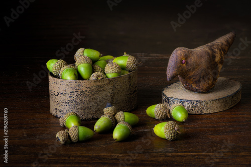 Still life with acorns and box with bird sculpture on lid.
