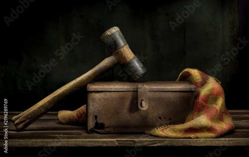 Old hammer resting on rusted metal box in vintage still life.