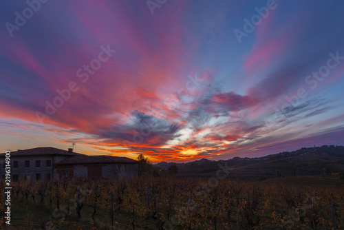 Sunset illuminating clouds over a building and vineyard rows in a rural landscape in the Collio Region, Friuli, Italy