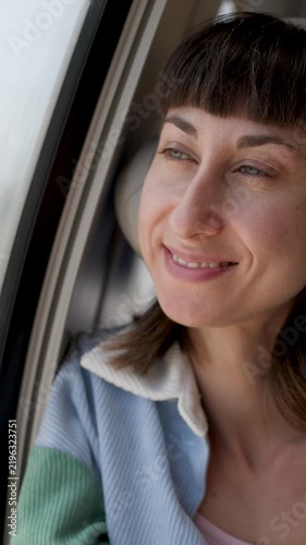 vertical shot. Young woman listening to music in earphones while traveling by train. relaxed face. passenger of the train. 
