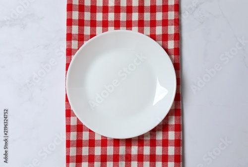 Obraz na płótnie White plate with checkered towel on marble background