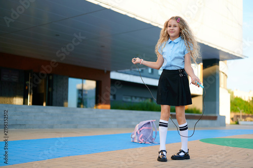 Fotografía Happy schoolgirl jumping rope outdoors during back to school season
