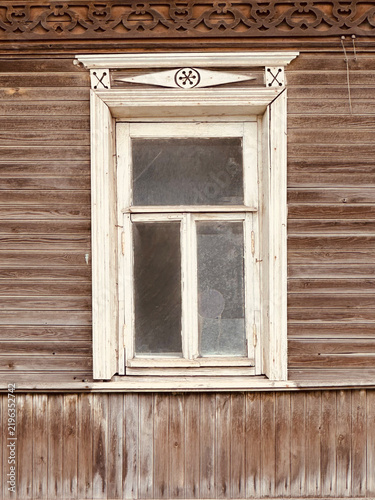 Weathered  russian Wooden Window with Carved White Frame on a Rustic Log Cabin Wall


