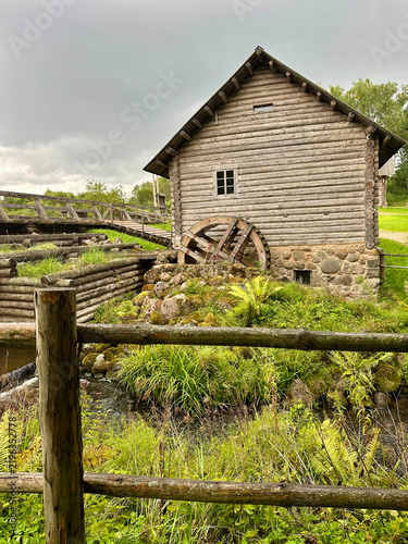 Old Wooden Watermill with Stone Foundation in a Rural Landscape Under a Dramatic Sky