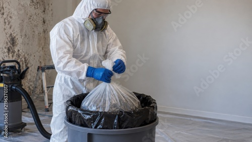 Mold cleanup worker sealing hazardous waste bag