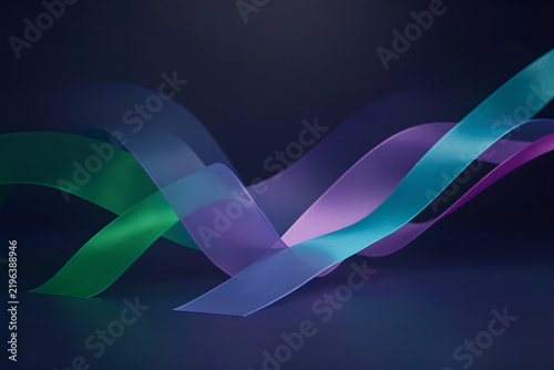 Abstract satin ribbons glow above a matte midnight-blue surface with emerald hues