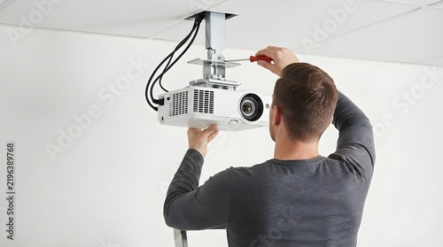 Technician Installing Ceiling Mounted Projector With Screwdriver