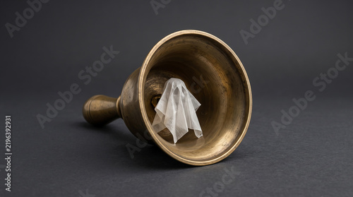 Antique Brass Hand Bell Containing a Trapped Paper Ghost on Dark Background