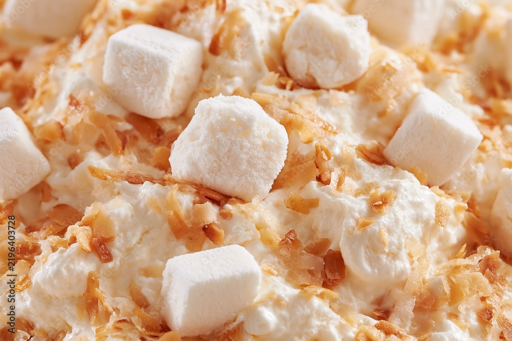 Obraz premium Macro detail shot of ambrosia salad featuring whipped cream, toasted coconut, and marshmallows on a textured surface, highlighting the ingredients and presentation style