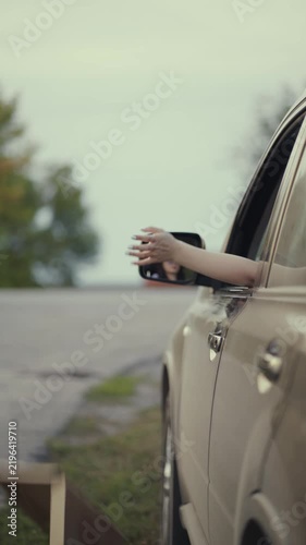 Woman throws pizza and burger boxes out of the car window while driving along a rural road.