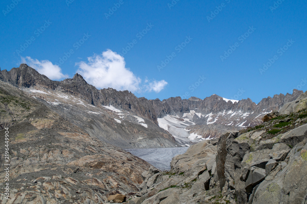 Obraz premium Panoramic view of the majestic Rhône Glacier in the Swiss Alps surrounded by rugged rocky mountain peaks under a clear blue sky