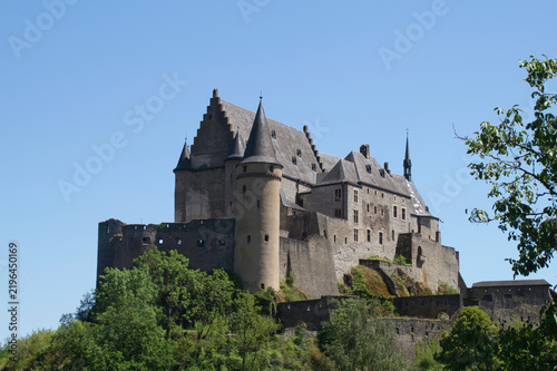 Vianden Castle stands majestically above a forested hillside in Luxembourg, showcasing impressive medieval architecture and centuries of history.
