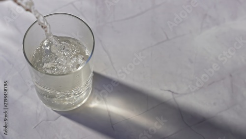 Фотография A glass is filled with sparkling water on a marble surface