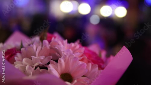 Pink chrysanthemum bouquet wrapped in paper with blurred festive bokeh lights, romantic delicate gift for celebration, wedding, birthday, love, anniversary and surprise beautiful