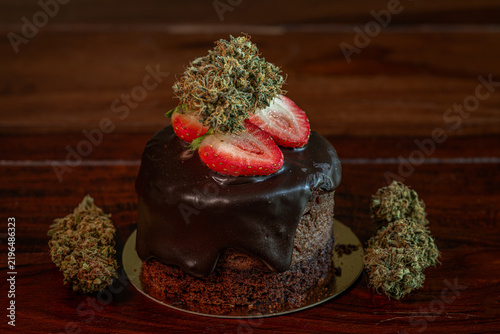 Chocolate strawberry fruit brown cake wooden table with marijuana flower blooms