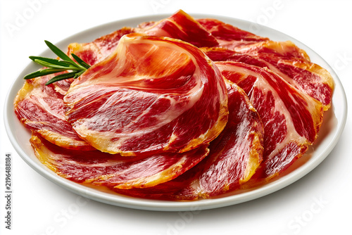 Cured meat slices arranged on a white plate with a sprig of rosemary