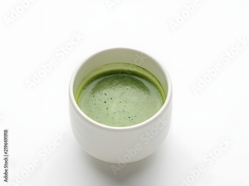 White ceramic cup filled with fresh green smoothie against clean studio background
