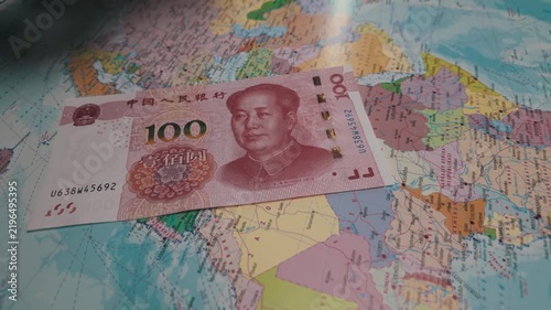 Chinese yuan against the backdrop of a world map. One-hundred-yuan banknotes are scattered across the world map. Concept of economic wars.
