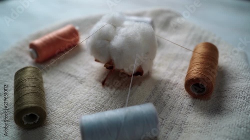 A cotton boll on a rotating table. Threads are emerging from the cotton boll.