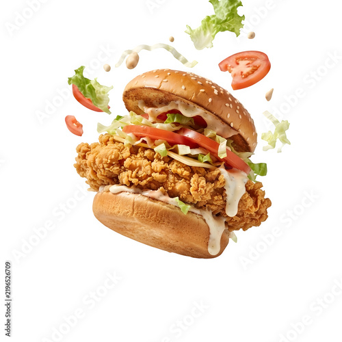 Crispy fried chicken sandwich with fresh lettuce and tomato slices floating, isolated on transparent background