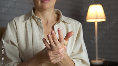 Woman with arthritis pain massaging hands. Unrecognizable woman massaging her painful hand and finger joints due to arthritis, rheumatism, or carpal tunnel syndrome, trying to relieve ache