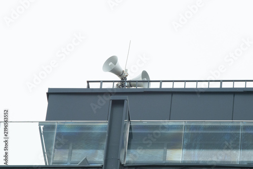 Canvastavla Public address horn loudspeakers on a modern building roof against a grey sky