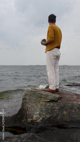 Man Throwing Stones Into the Sea on a Cloudy Day at the Beach