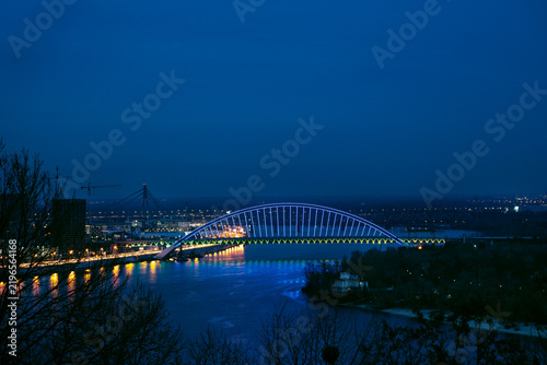 Bild auf Leinwand Illuminated Podilsko-Voskresensky bridge with blue light reflections on Dnipro r