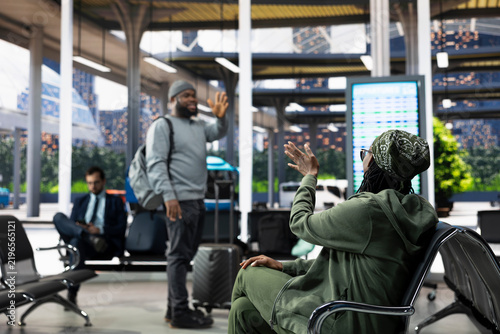 Canvastavla Woman waves goodbye from a bus terminal bench as her companion leaves with a backpack during weekday travel, offering a farewell before departure in the shuttle station and an emotional parting
