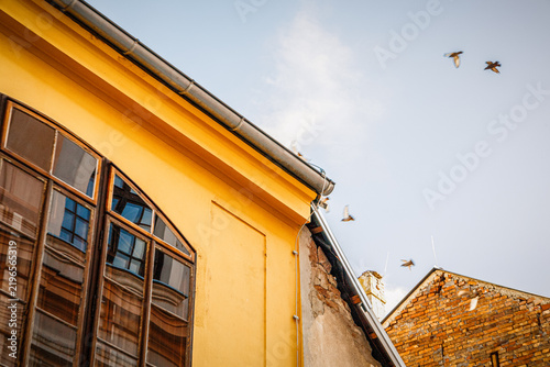 Foto Bright yellow building exterior featuring windows and decorative elements in day
