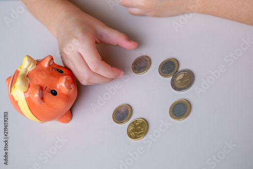 Konstfotografi Child hand putting coin orange piggy bank savings money finance education learni